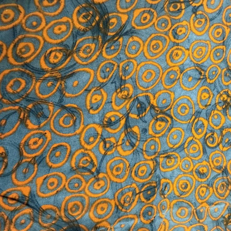 Bedruckter Stoff: orangefarbene Kreise und Ringe auf blaugrauem Grund