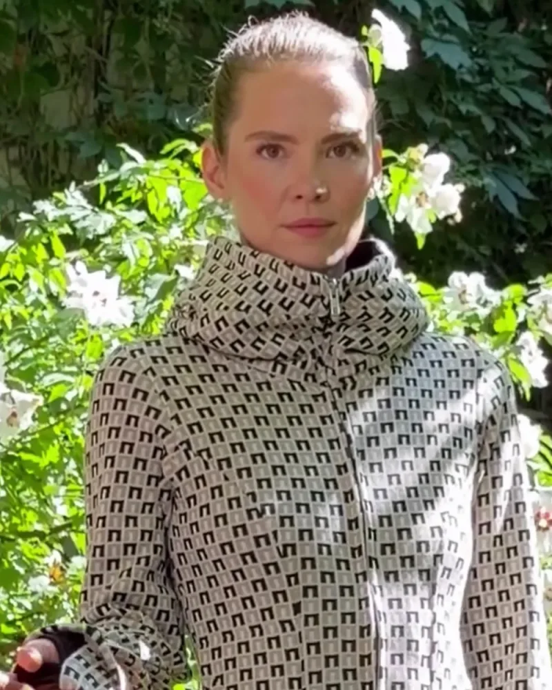 Elisabeth in der hellen Strickjacke Nayana mit grafischem Muster und hohem Schalkragen, dazu eine petrolfarbene Hose