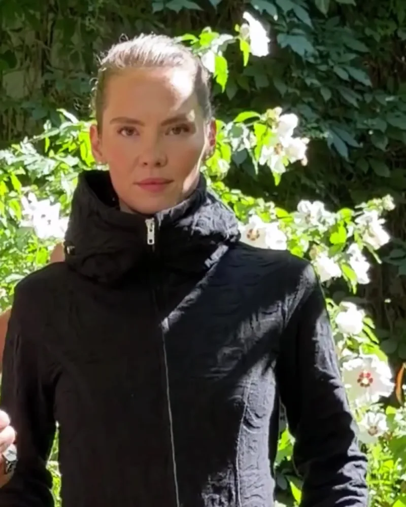 Elisabeth in der schwarzen Strickjacke Nayana mit erhabenem Muster, die Hände in den Taschen