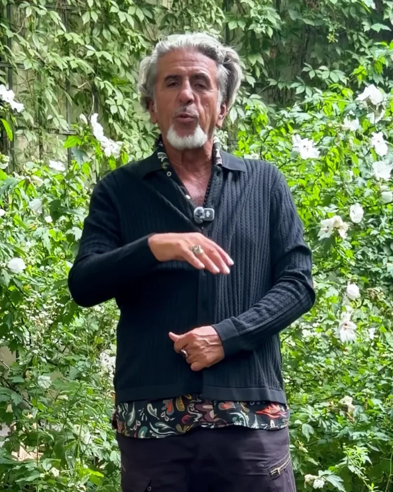 Hamid steht im Garten in der offenen Strickjacke Nox
