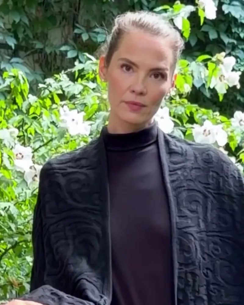 Elisabeth im schwarzen gestrickten Poncho Jacqueline, Hamid zeigt die Kante des Stoffs