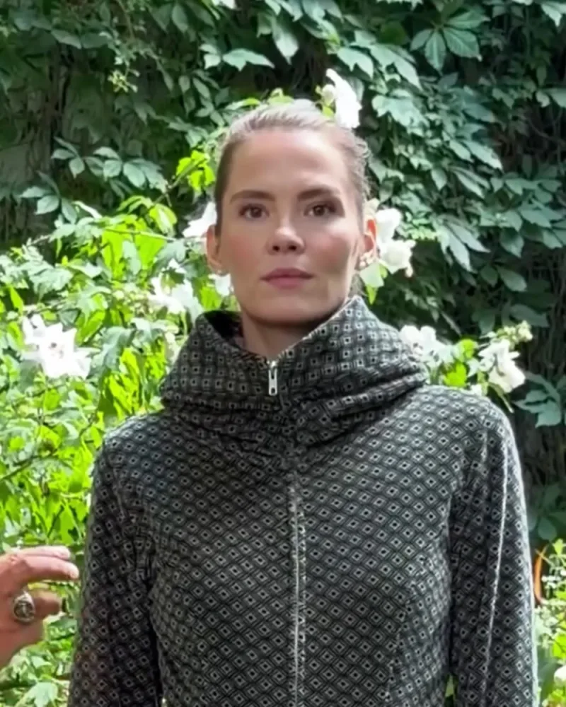 Elisabeth in der grau-schwarz gemusterten Samtjacke Jessy mit hohem Kragen, dazu eine petrolfarbene Hose