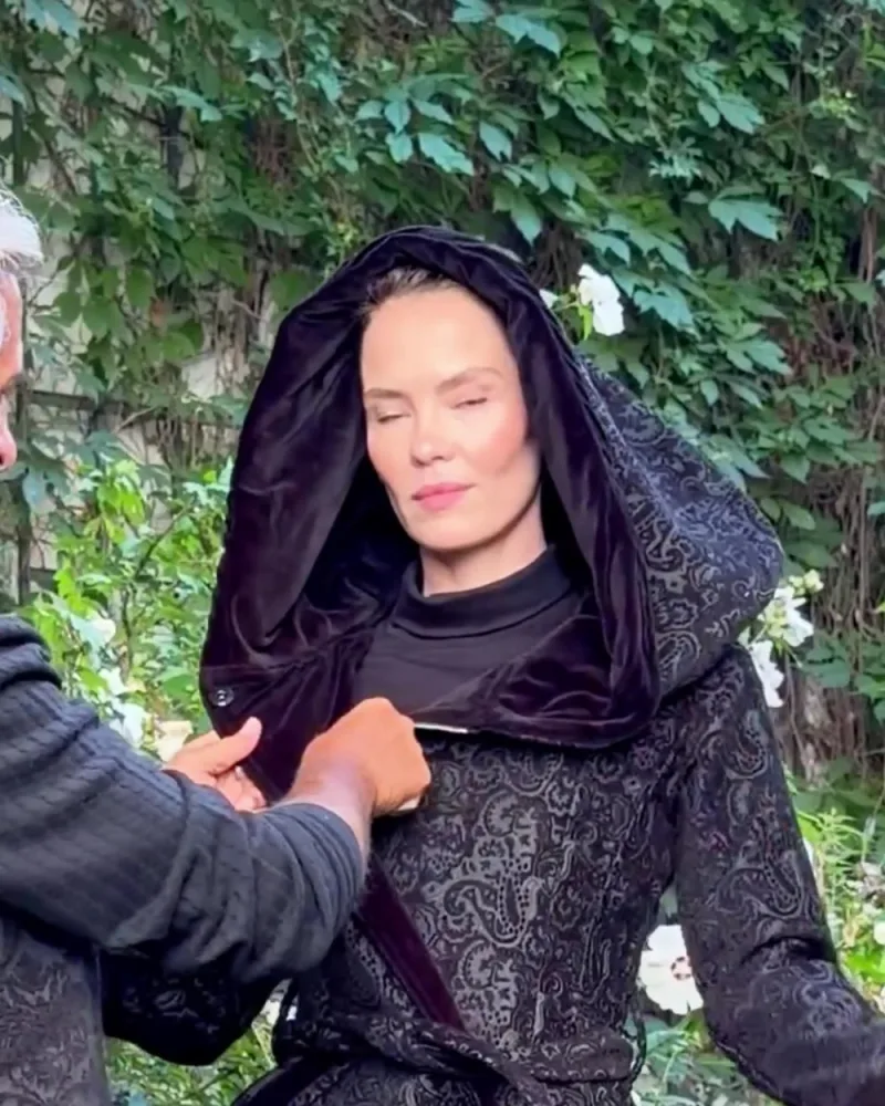 Hamid hilft Elisabeth, die große Kapuze des Mantels Mara aufzusetzen