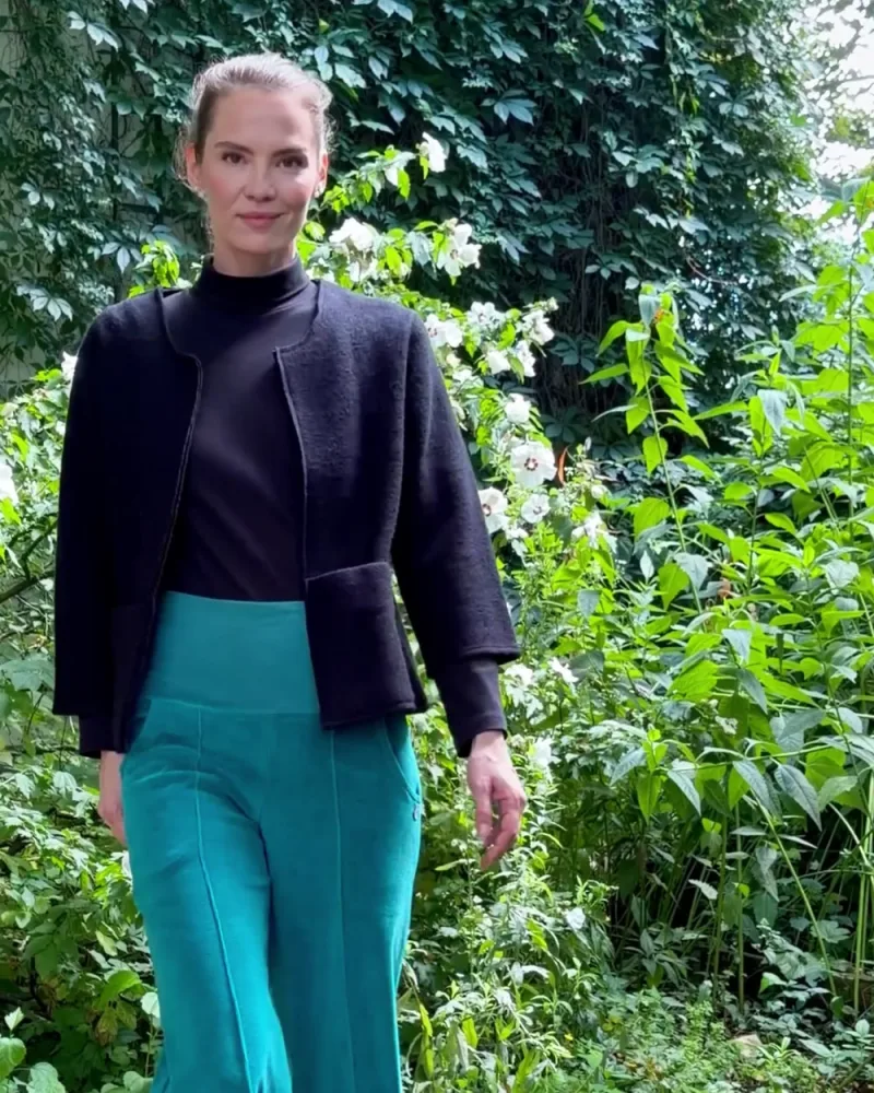 Elisabeth geht in Jacke Nora und Hose Ninella durch den Garten