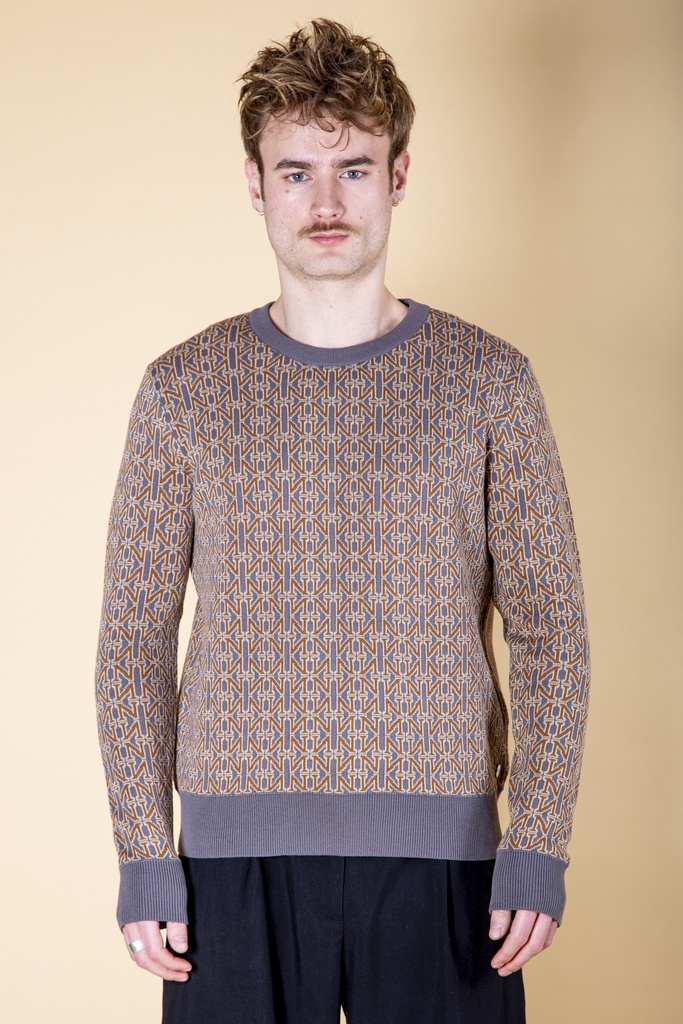 Vorderansicht bis zur Hüfte: braun-grauer Pullover aus Strick-Jacquard mit ockerfarbenen und blauen Streben, graublauem Rippbund.