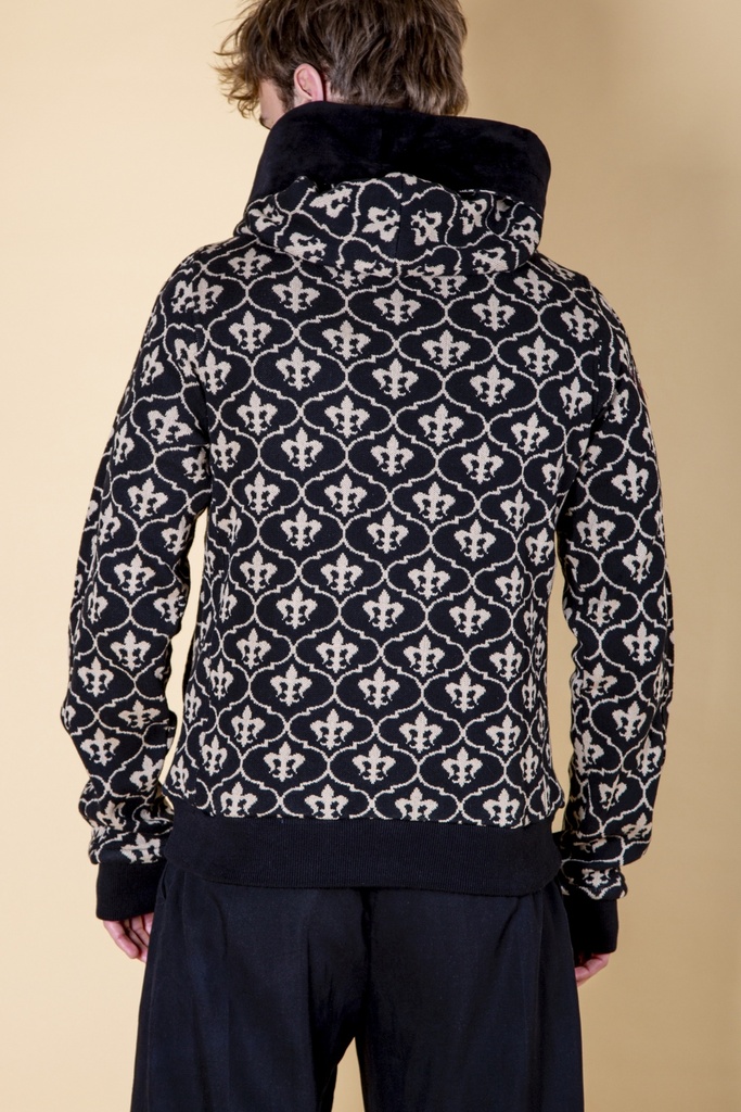 Rückansicht bis zur Hüfte: das weiße Lilienmuster bedeckt den schwarzen Strick-Jacquard-Pullover und den als Schal liegenden Kapuzenteil.