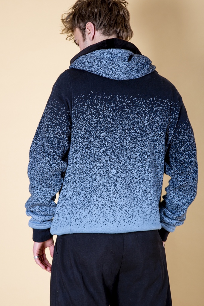 Rückansicht bis zur Hüfte: der blau verlaufende Strick-Jacquard-Pullover zeigt den breiten Kapuzenschal und Sprenkel von Dunkel- zu Hellblau.