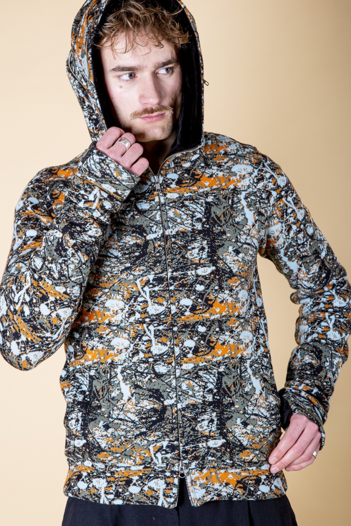 Nahaufnahme mit aufgesetzter Kapuze: die orange-grau gemusterte Strick-Jacquard-Jacke zeigt den hohen Schalkragen und mittigen Reißverschluss.