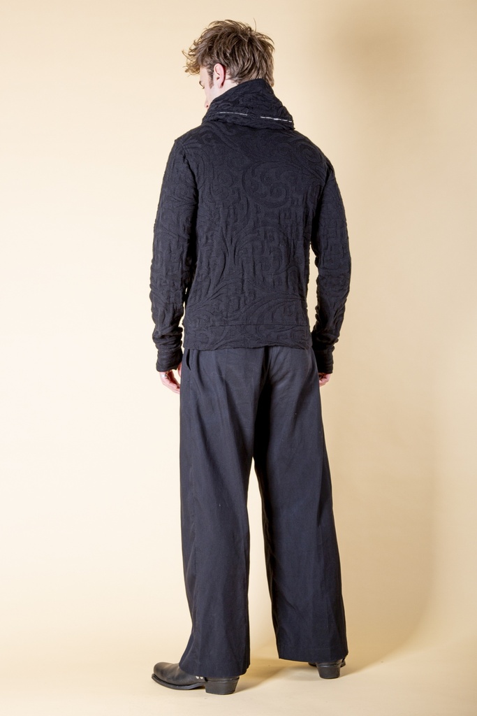 Rückansicht in ganzer Länge: schwarze Jacke aus Strick-Jacquard mit reliefartigem Ornamentmuster, hohem Kragen und langen Ärmeln mit Stulpen.