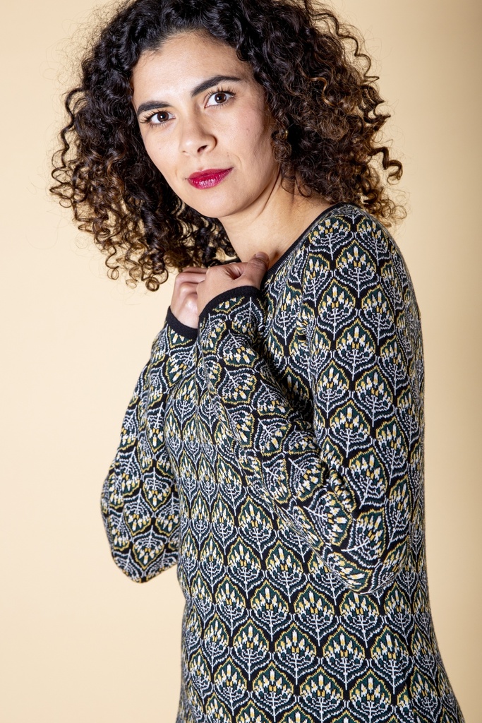 Seitenansicht von Schulter und Ärmel: das dunkelblaue Kleid aus Strick-Jacquard zeigt gelb-weiße Blütenreihen und eine schwarze Ausschnittkante.