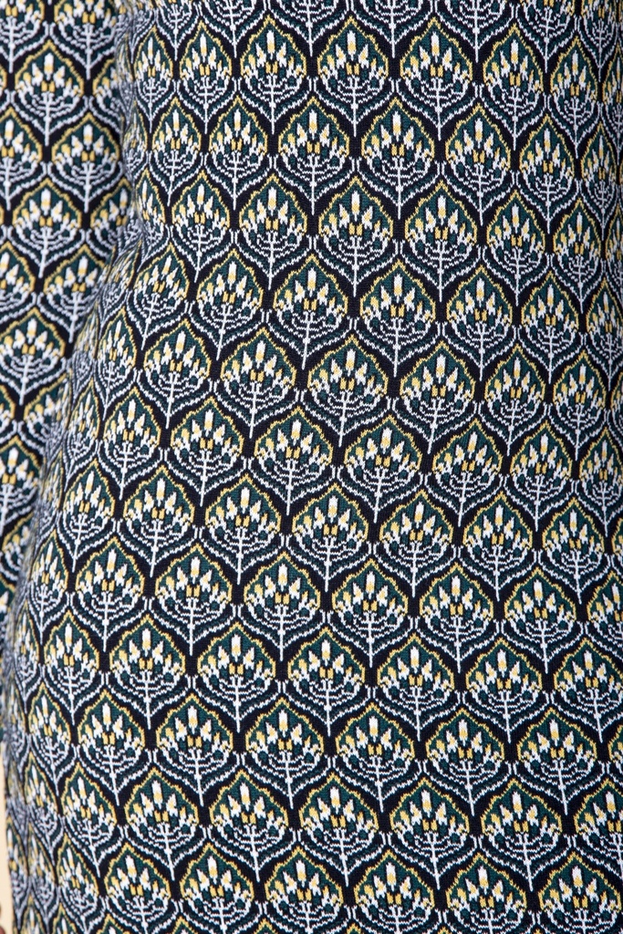 Makroaufnahme des Kleid-Stricks: gelb-weiße fächerförmige Blüten stehen in dichten Reihen auf dunkelblauem Jacquardgrund.