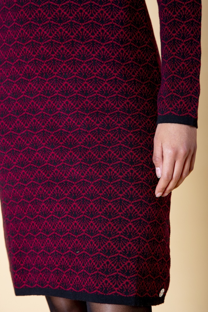 Nahaufnahme des Rocks: das dunkelrote Kleid aus Strick-Jacquard zeigt schwarzes Rautenmuster, dunklen Saum und kleine runde Markierung an der Seite.