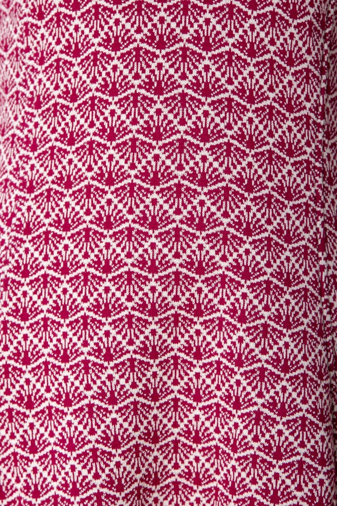 Makroaufnahme des Kleid-Stricks: dunkelrote Fächer stehen in dichten waagerechten Reihen auf weißem Jacquardgrund.