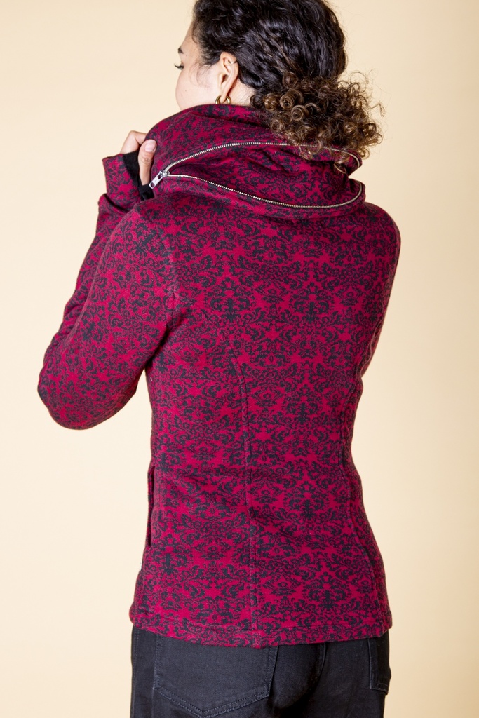 Rückansicht bis zur Hüfte: das dunkelrote und schwarze Barockmuster bedeckt die Strick-Jacquard-Jacke, ein zweiter Reißverschluss verläuft am Kapuzenkragen.