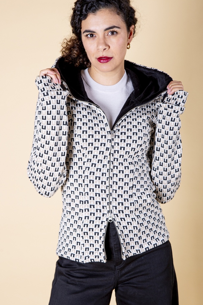 Vorderansicht bis zur Hüfte: weiß-schwarz gemusterte Jacke aus Strick-Jacquard mit breitem Kapuzenschal, Reißverschluss und dunklem Innenfutter.