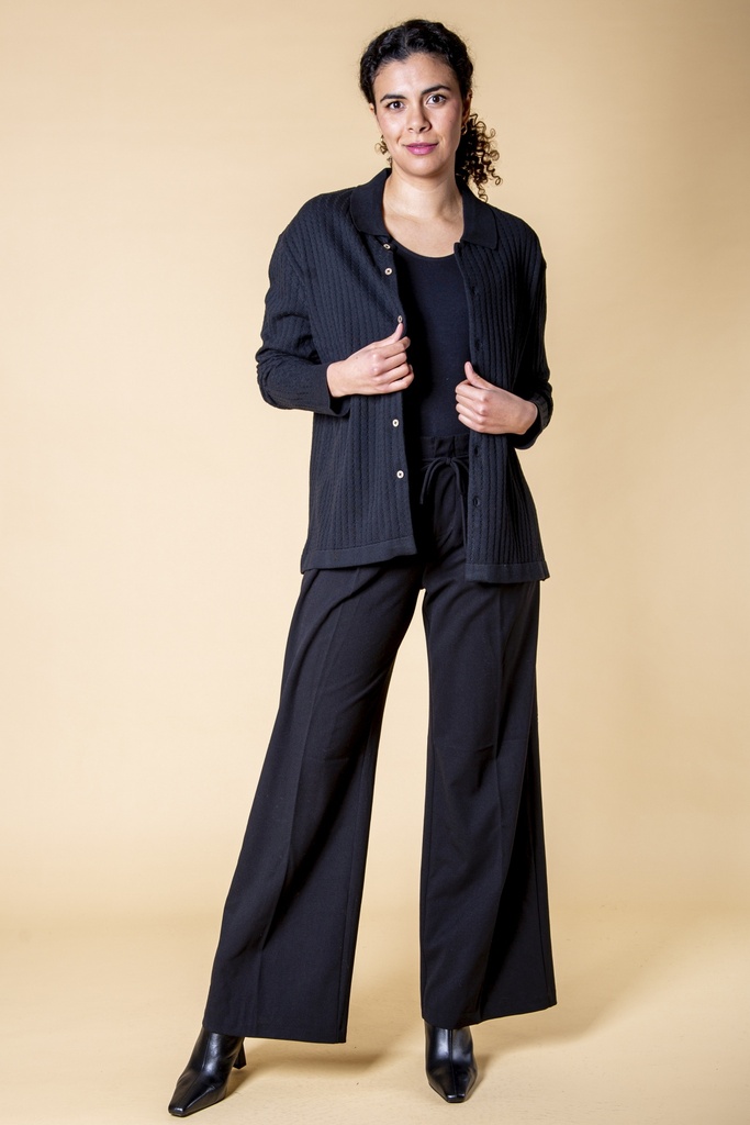 Ganzkörperansicht an einer Frau getragen: die offene schwarze Strickjacke über einem schwarzen Oberteil und einer weiten Hose.