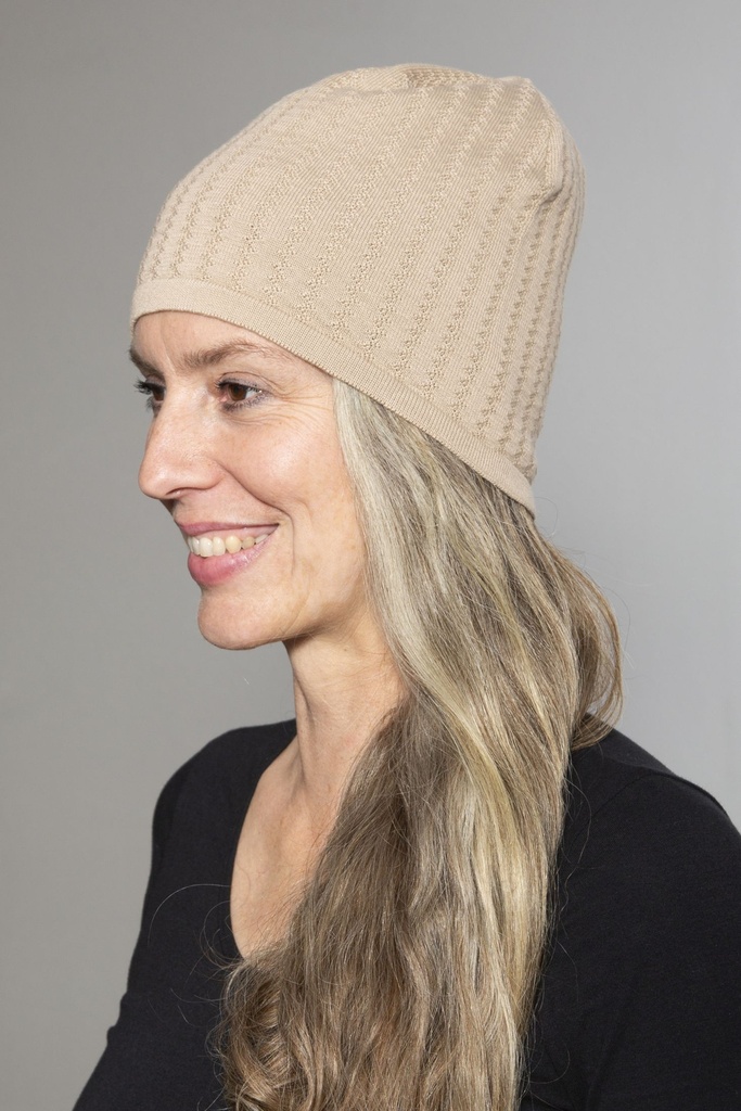 Porträt im Profil: die beige Mütze steht hinten weich ab, das Zopfmuster läuft senkrecht über den Kopf.