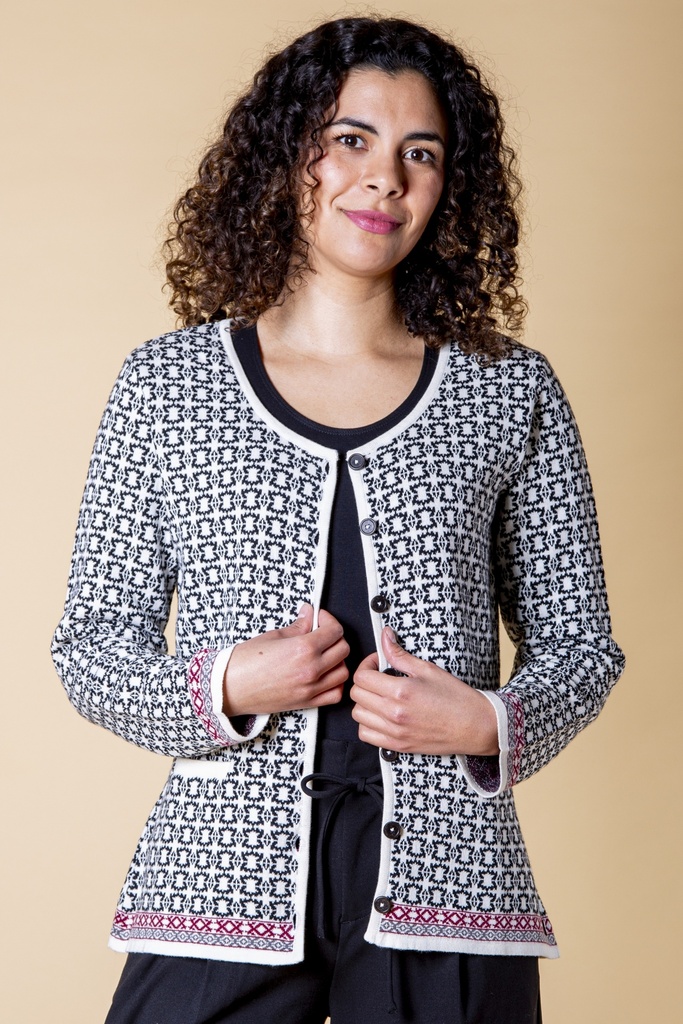 Ansicht bis zur Hüfte: die gerade geschnittene Strickjacke zeigt die schwarze Knopfleiste, das grafische Muster und rosafarbene Saumdetails.