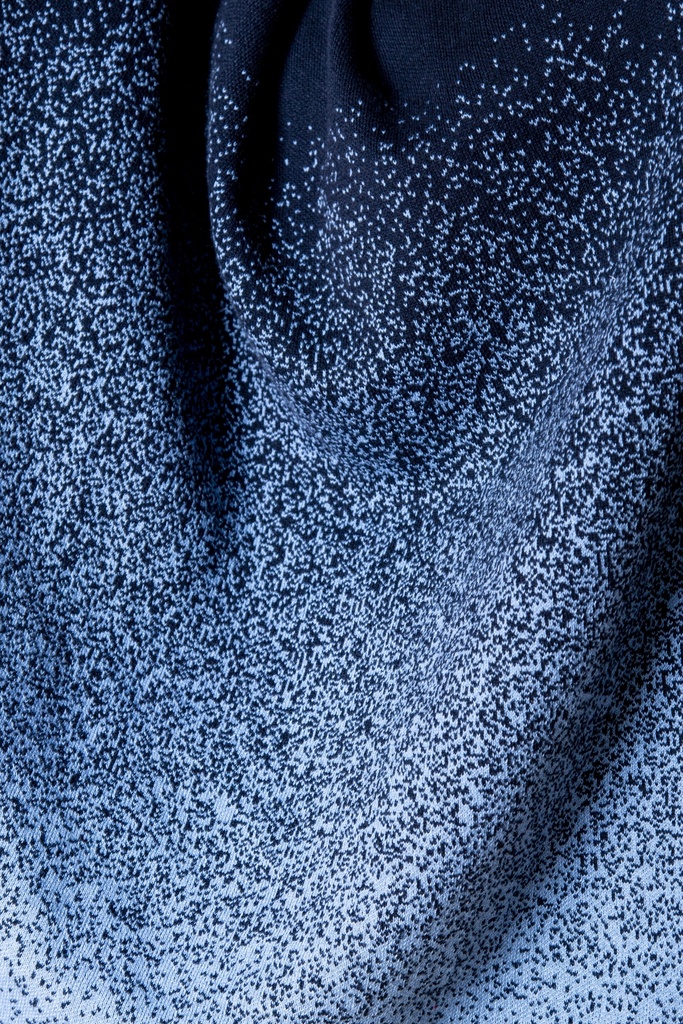 Makroaufnahme des Strick-Jacquards: helle blaue Sprenkel verdichten sich am Saum zu einem Farbverlauf aus Dunkel- und Hellblau.