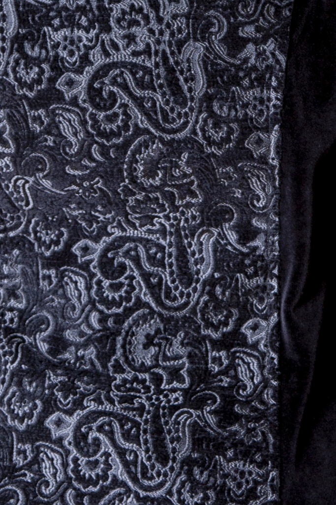 Makroaufnahme des Brokateinsatzes: silbergraue Paisley-Ornamente zeichnen sich reliefartig auf dem schwarzen Stoff der Jacke ab.