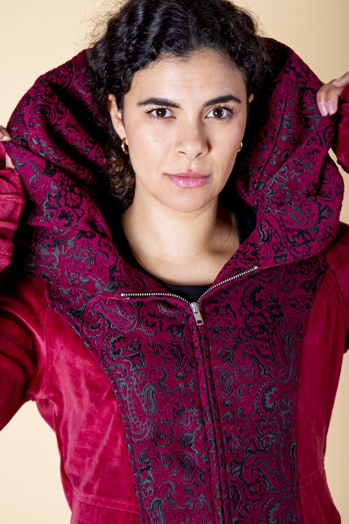 Nahaufnahme des großen Kapuze-Schalkragens: schwarz-rote Paisley-Ornamente liegen eingerahmt von dunkelrotem Samt über den Schultern.