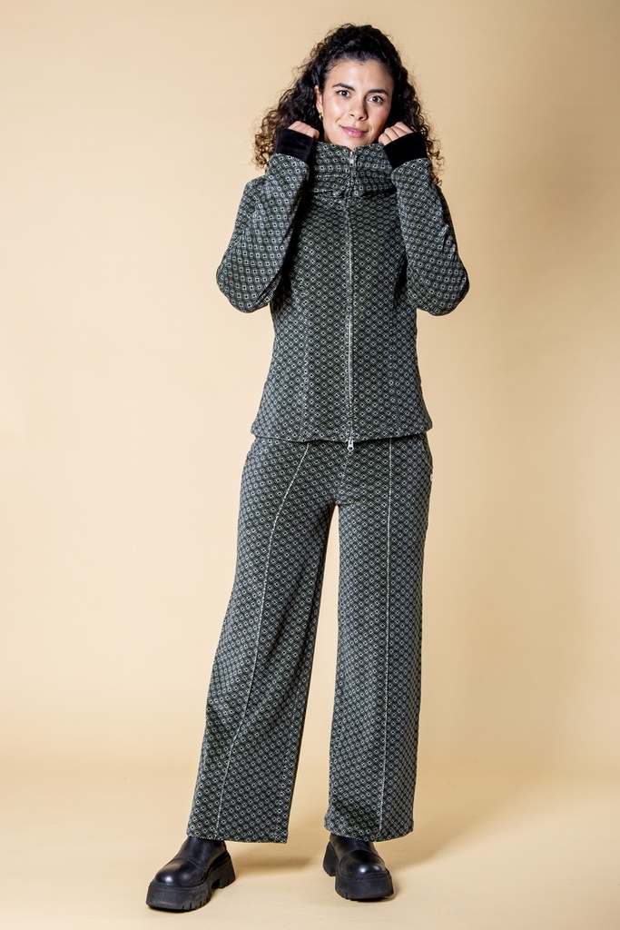 Ganzkörperansicht im Kombinationslook: die schwarz-grau gemusterte Samthose fällt gerade von der Hüfte bis zum Saum und hat seitliche Eingrifftaschen.