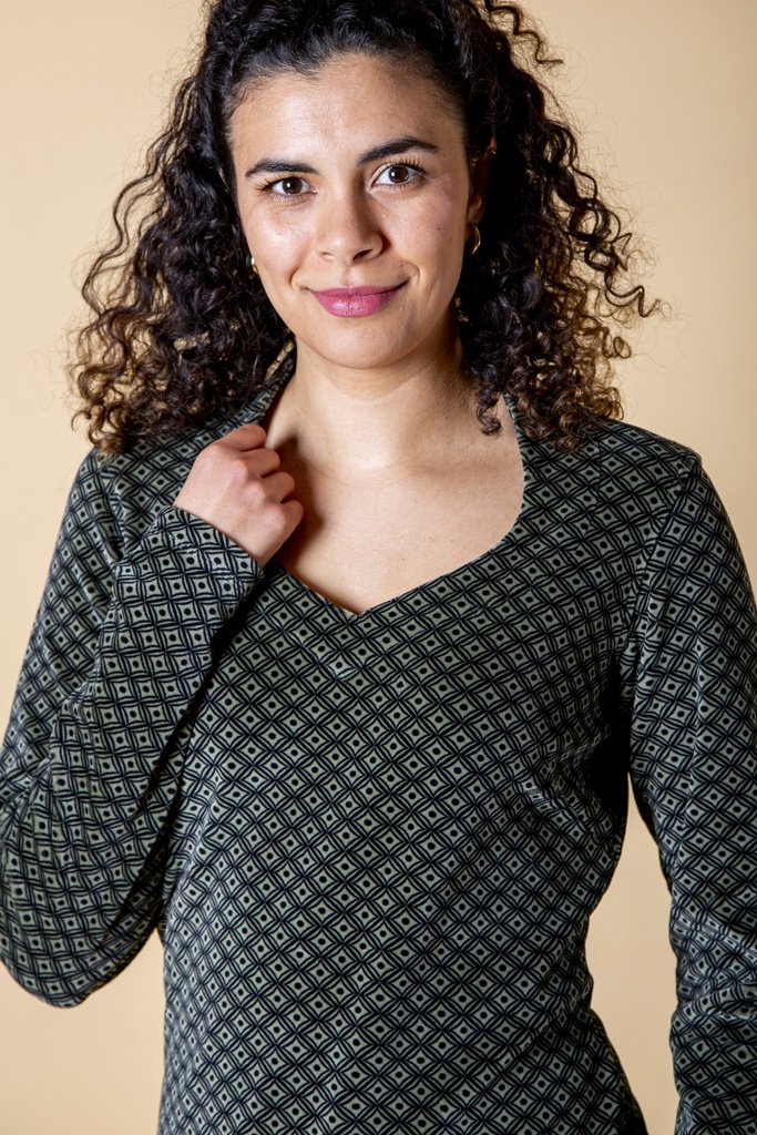 Halbnahe Ansicht von vorn: Das schwarzgraue Kleid aus Samt zeigt den weiten Ausschnitt und das feine Rautenmuster aus kleinen hellen und dunklen Formen.