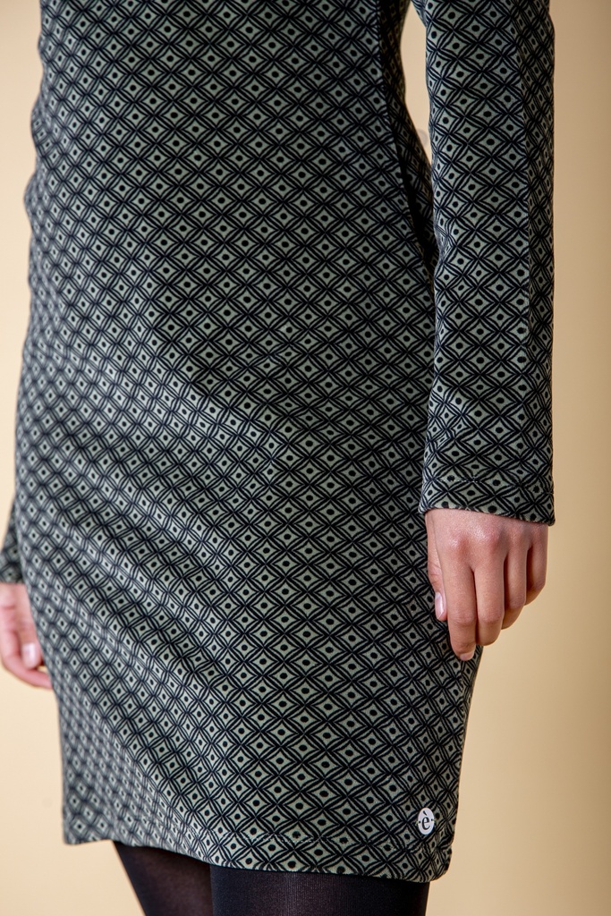Detailansicht: Das schwarzgraue Kleid aus Samt zeigt das feine Rautenmuster, den geraden Saum und eine kleine helle runde Verzierung an der Seitennaht.