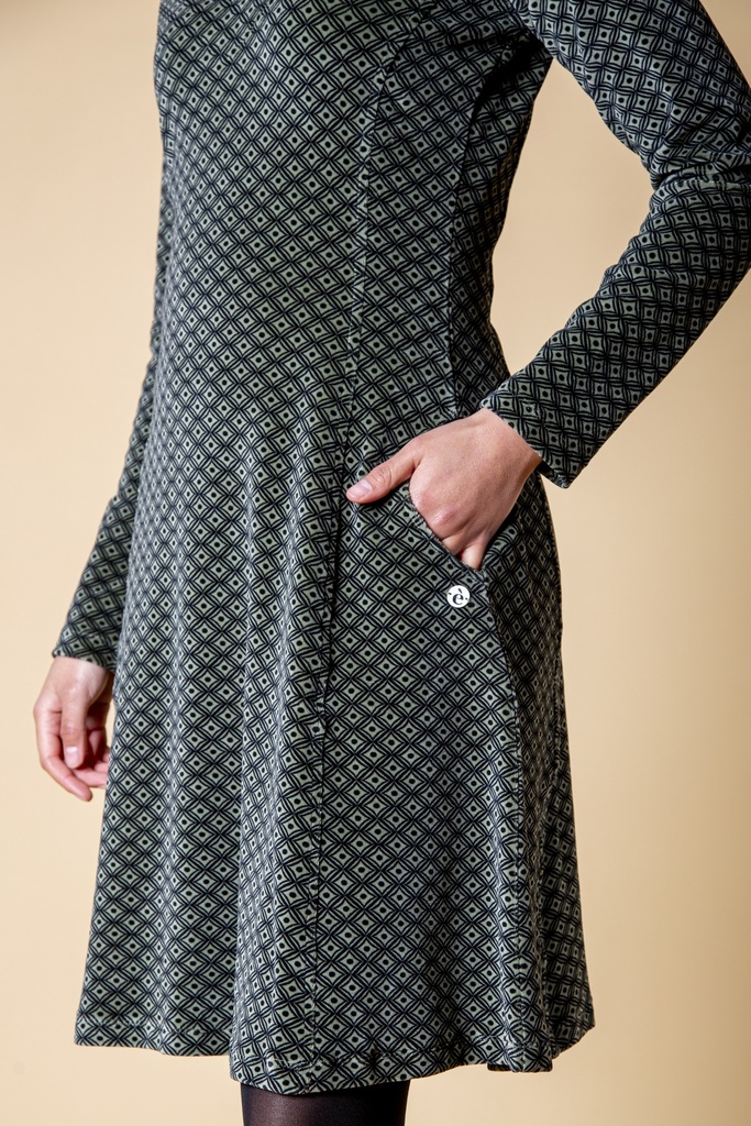 Detailansicht: Das schwarzgraue Kleid aus Samt zeigt die seitliche Eingrifftasche, das feine Rautenmuster und eine kleine helle runde Verzierung.