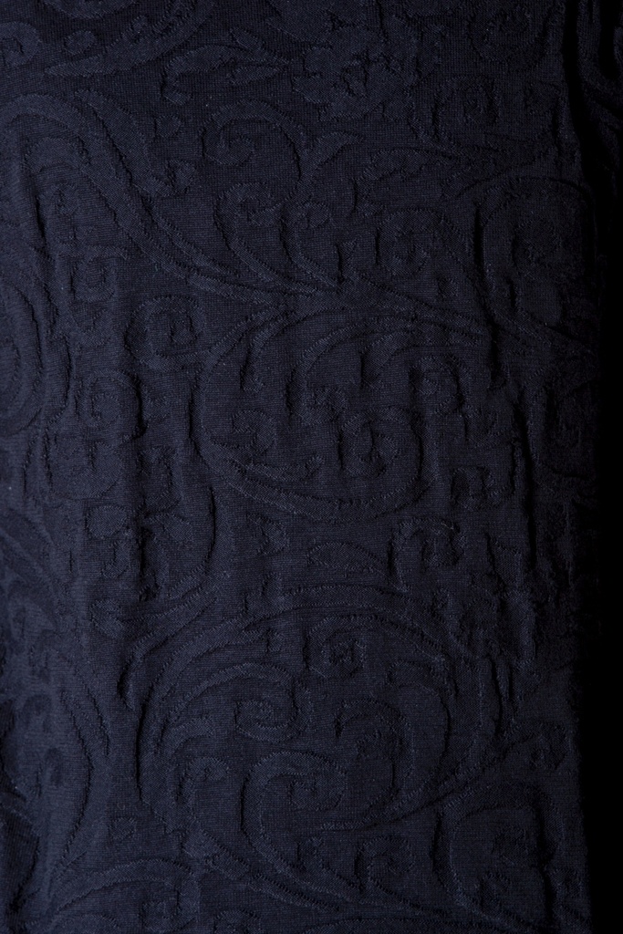 Makroaufnahme des Strick-Jacquards: die schwarze Oberfläche zeigt ein erhabenes geometrisch-organisches Muster mit dicht gestrickter Struktur.