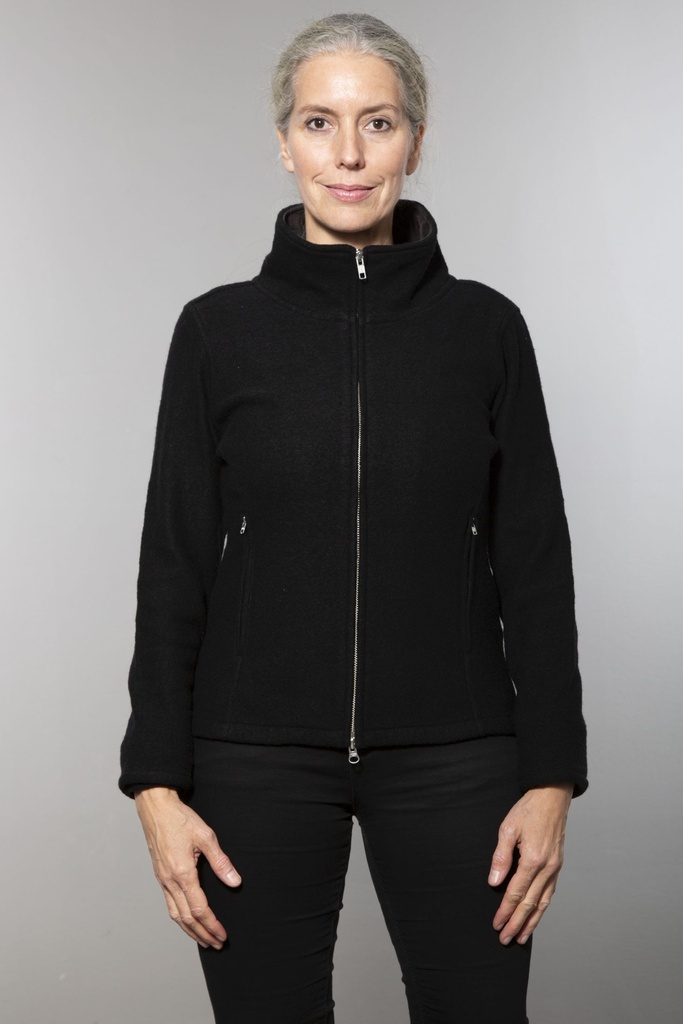 Oberkörper halbnah: kurze schwarze Wolljacke mit schrägem Reißverschluss und Stehkragen, offen über einem schwarzen Shirt getragen.